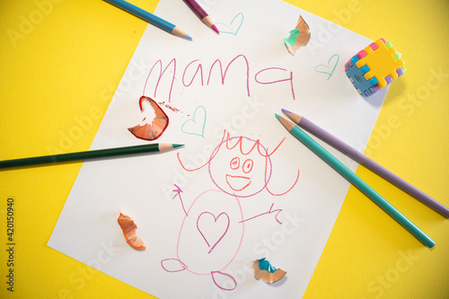 child drawing for mom with color pencils on yellow background in Spanish