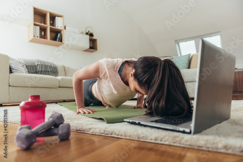 Woman training at home and using laptop