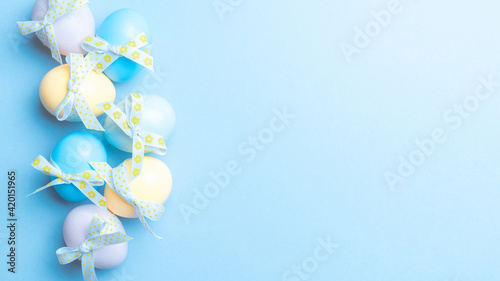 Easter pattern. Colorful egg with tape ribbon on pastel blue background in Happy Easter decoration. Spring holiday top view concept.