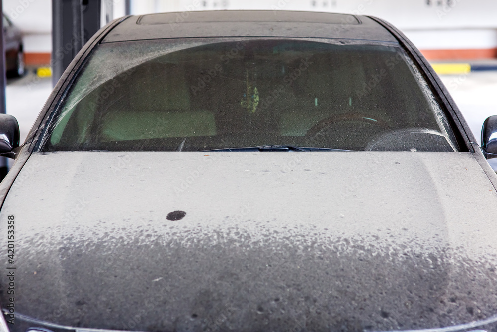 dirty black car with wiped windshield wipers covered with a layer of