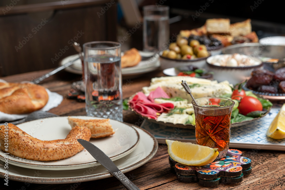 Delicious rich Traditional Turkish breakfast include tomatoes, cucumbers, cheese, butter, eggs, honey, bread, bagels, olives and tea cups. Ramadan Suhoor aka Sahur (morning meal before fasting). Delicious rich Traditional Turkish breakfast include tomatoes, cucumbers, cheese, butter, eggs, honey, bread, bagels, olives and tea cups. Ramadan Suhoor aka Sahur (morning meal before fasting).