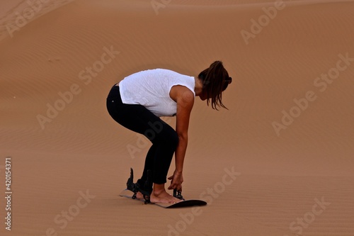 Girl snowboarding in Sahara desert. Please note person is not recognizable as you can't see the face. 