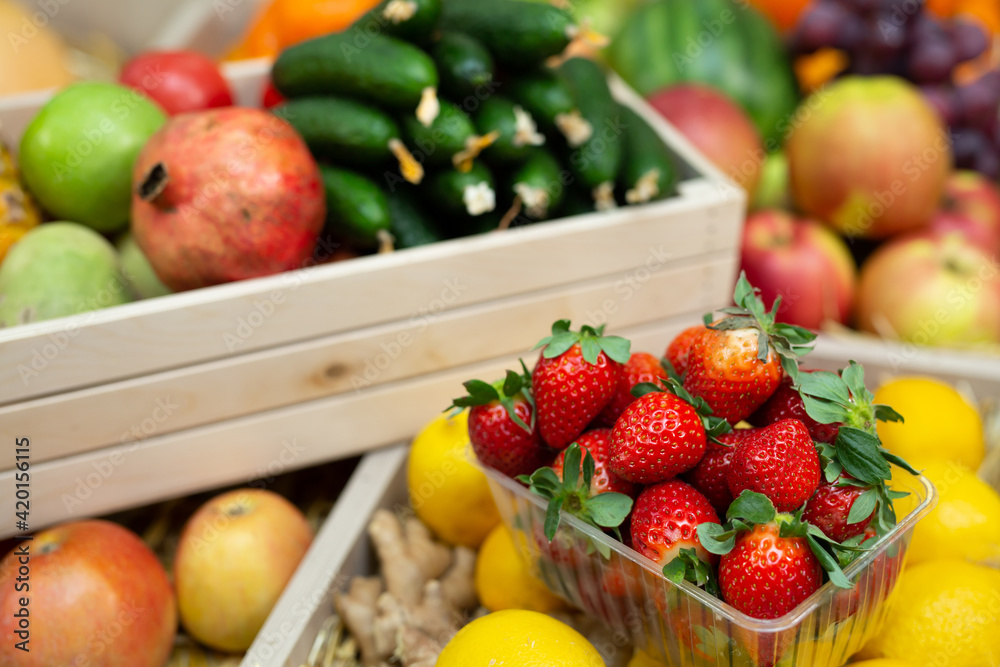 Tray of strawberries on the counter of a vegetable store among vegetables and fruits. Tray of strawberries on the counter of a vegetable store among vegetables and fruits.