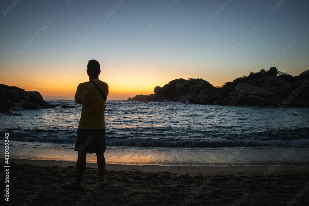 Hombre en la playa viendo el atardecer