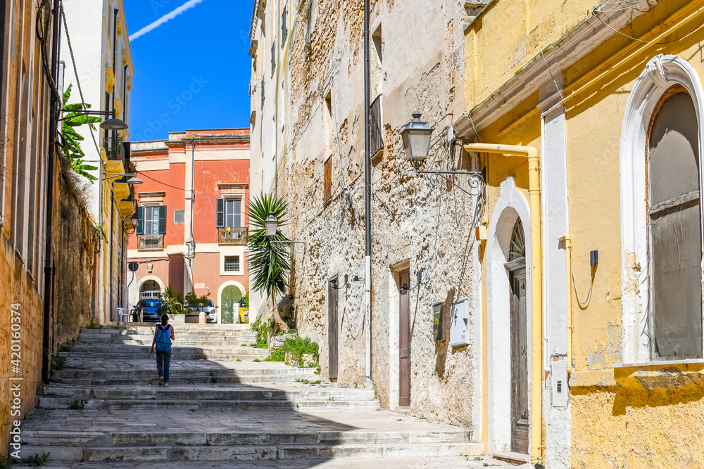 A young girl with a backpack walks home from school in the historic center of the city of Brindisi, Italy, in the Puglia region