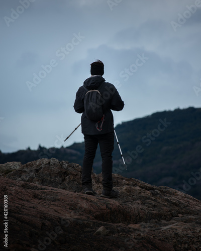 A person looking the mountains and the lake from a big rock