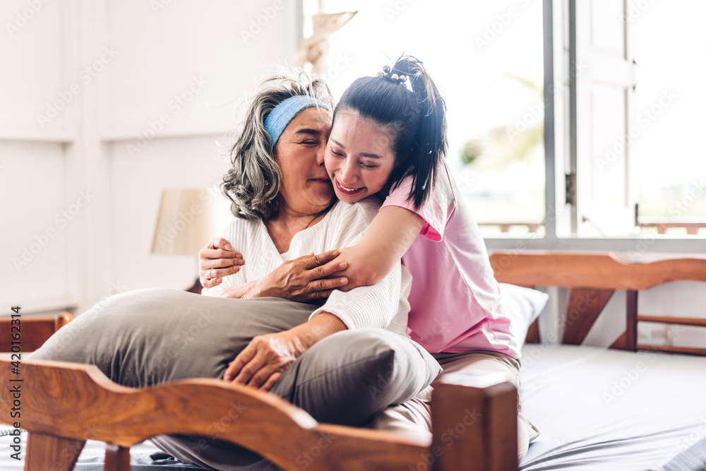 Obraz premium Portrait of enjoy happy love asian family senior mature mother and young daughter smiling laughing embracing and having fun hug together in moments good time at home