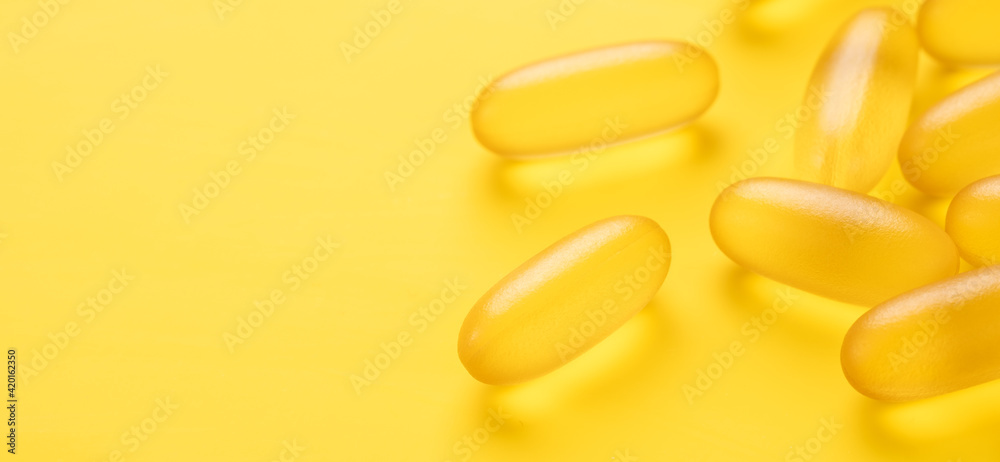 Horizontal banner with close up Omega 3 capsules on yellow background. Fish oil softgels. Copy space for your text - Image Horizontal banner with close up Omega 3 capsules on yellow background. Fish oil softgels. Copy space for your text - Image