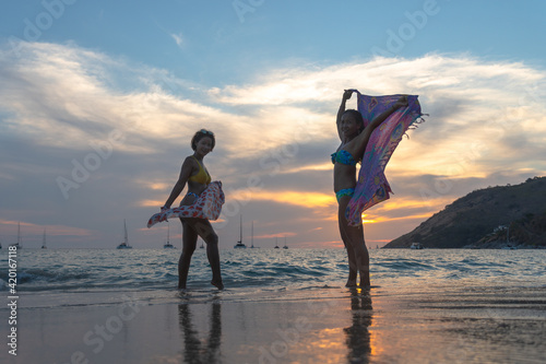 Two women posing beautiful on the beach. During the COVID-19 outbreak not many tourists on Nai Harn beach. but still have local people on the Nai Harn beach Phuket Thailand..