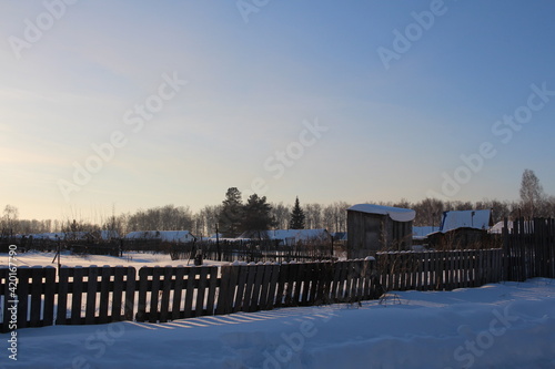 a wooden fence blocks an unfinished house in the winter in the village © Алла Мосурова