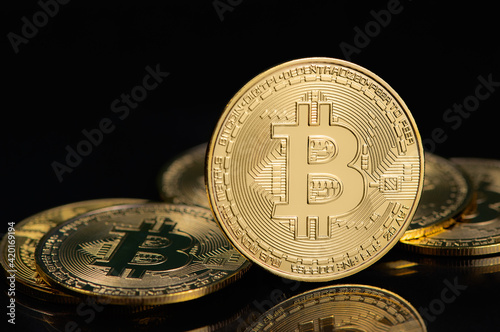 Bitcoin e-cryptocurrency on black background. Peer-to-peer payment system. Golden virtual currency coin. High quality photo