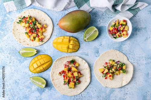 Tortillas with fresh mango salsa on color background