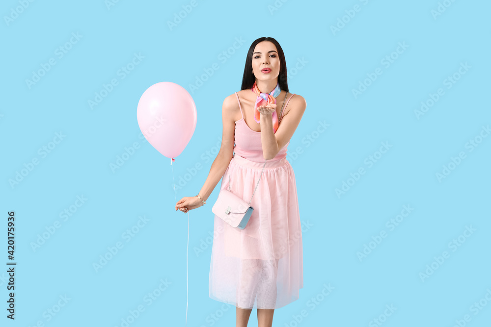 Beautiful young woman with balloon blowing kiss on color background Beautiful young woman with balloon blowing kiss on color background