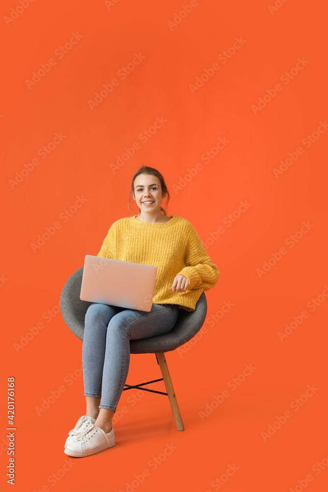 Beautiful young woman with laptop sitting in armchair on color background Beautiful young woman with laptop sitting in armchair on color background
