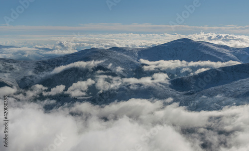 In the mountains above the clouds. Snow-covered slopes and peaks.