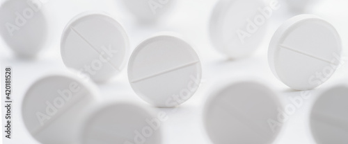 Fototapeta Naklejka Na Ścianę i Meble -  A pile of white pills scattered on a bright white background. Selective focus.