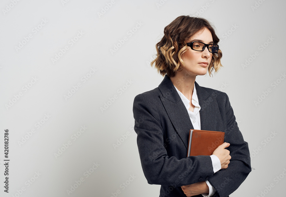 Business woman in a classic suit with a book in her hands on a light background indoors Business woman in a classic suit with a book in her hands on a light background indoors