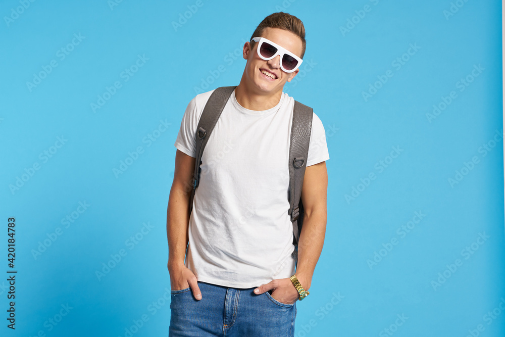 Fototapeta premium Cheerful young guy with backpack studio blue background