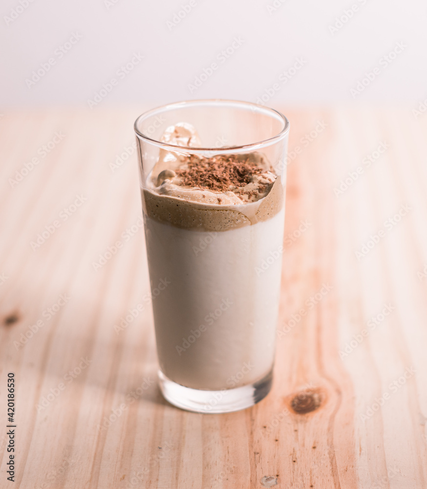 Homemade Dalgona coffee glass in a wooden textured tabletop. whisked instant coffee topping and fresh milk in the bottom making the delicious Korean drink. Trendy beverage in modern days. Homemade Dalgona coffee glass in a wooden textured tabletop. whisked instant coffee topping and fresh milk in the bottom making the delicious Korean drink. Trendy beverage in modern days.