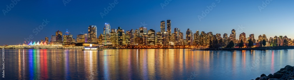 Night view of Vancouver downtown skyline panorama after sunset. Colorful buildings lights reflections on waterfront harbor. British Columbia, Canada. Night view of Vancouver downtown skyline panorama after sunset. Colorful buildings lights reflections on waterfront harbor. British Columbia, Canada.