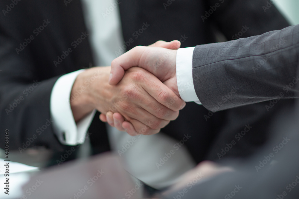 close up. business partners, confirming their agreement with a handshake. close up. business partners, confirming their agreement with a handshake.