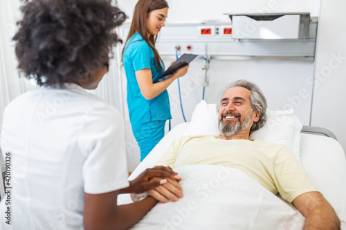 Healthcare concept of professional doctor consulting and comforting elderly patient in hospital bed or counsel diagnosis health. Medical doctor or nurse holding senior patient hands and comforting him