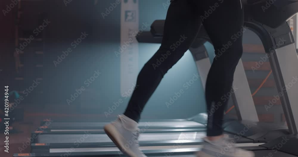Close up view of man legs in sneakers running on treadmill at gym, slow motion