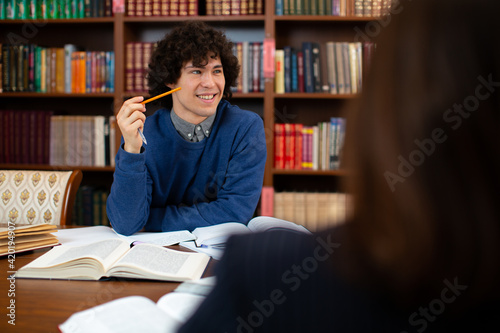 photo of a guy scientist who sits in the library  working on a project and smiling. Student science. High quality photo