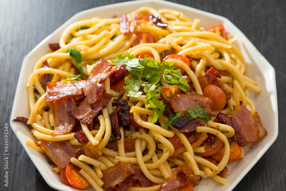 Spaghetti alla Amatriciana with bacon, tomatoes and dried chili on black wood table. Spaghetti alla Amatriciana with bacon, tomatoes and dried chili on black wood table.