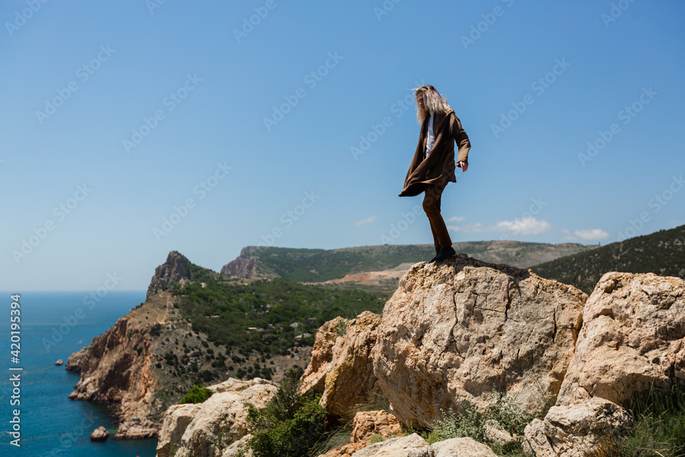 fellow hipster with long blond hair stands on top of a hill in the wind in sunny summer weather. High quality photo fellow hipster with long blond hair stands on top of a hill in the wind in sunny summer weather. High quality photo