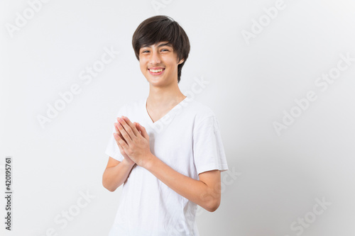 Smiling teen boy greeting with palms gesture pressed together on white background. photo