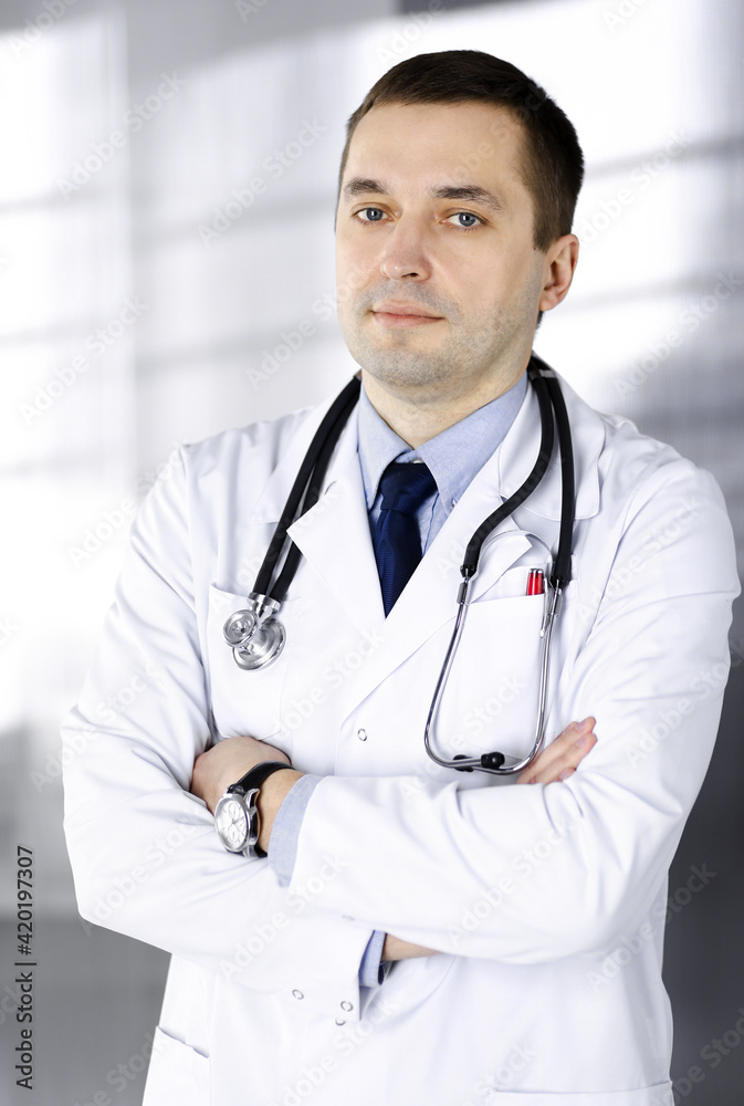 Professional doctor with a stethoscope is standing with crossed arms in a clinic. Perfect medical service in hospital. Medicine and healthcare concept