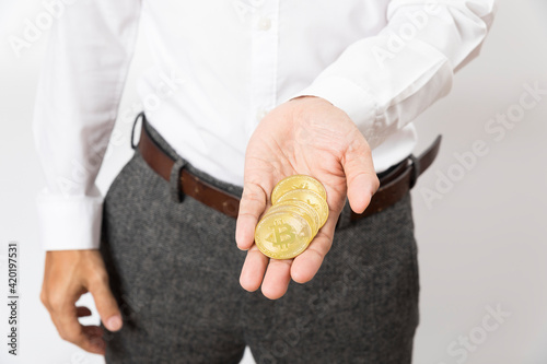 Business man in white shirt with a coin in his hand, cryptocurrency Bitcoin finance.