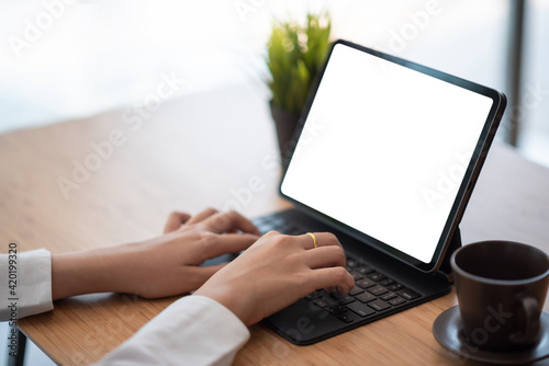 Business woman hand Printing using tablet blank white screen at a coffee shop. Mock up.