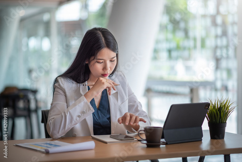 Asian business woman sitting in office looking smartphone.