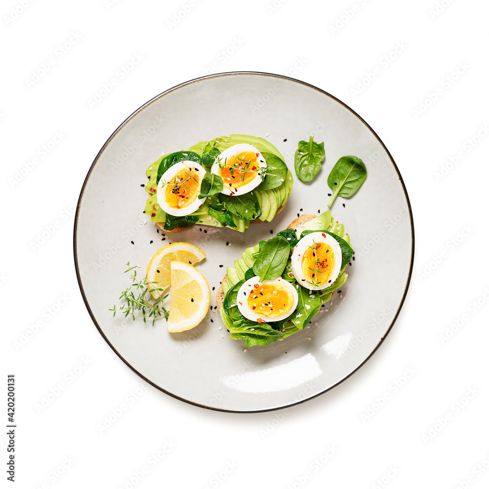 Healthy toast with sliced avocado, boiled eggs, spices and fresh spinach. Delicious breakfast or snack isolated on white background