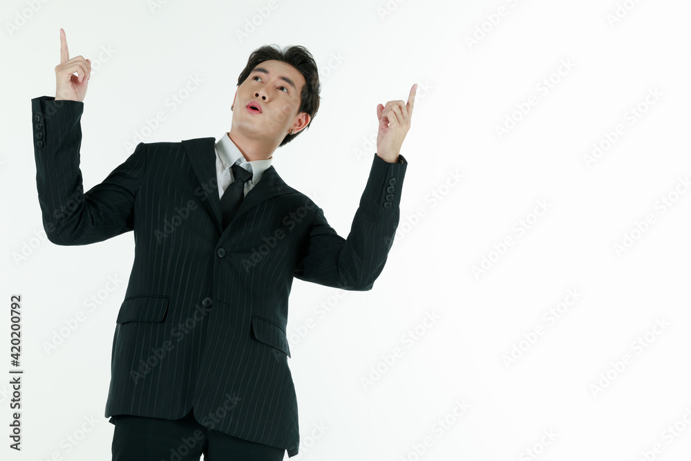 Portrait of self-confidence young and handsome Asian businessman in black suit standing in elegant pose and pointing finger, copy space studio shot isolated on white background Portrait of self-confidence young and handsome Asian businessman in black suit standing in elegant pose and pointing finger, copy space studio shot isolated on white background