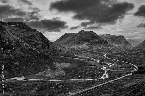 Flying drone epic black and white landscape image of Buachaille Etive Mor and surrounding mountains and valleys in Scottish Highlands on a Winter day