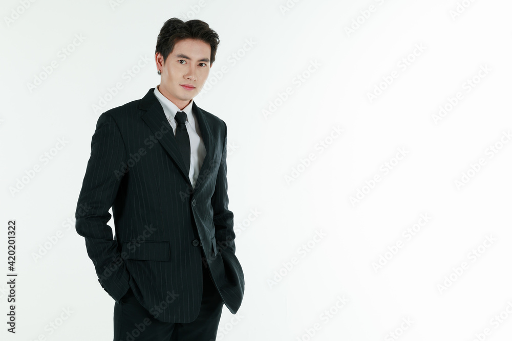 Portrait of self-confidence young and handsome Asian businessman in black suit standing in elegant pose with hands in pocket, copy space studio shot isolated on white background Portrait of self-confidence young and handsome Asian businessman in black suit standing in elegant pose with hands in pocket, copy space studio shot isolated on white background