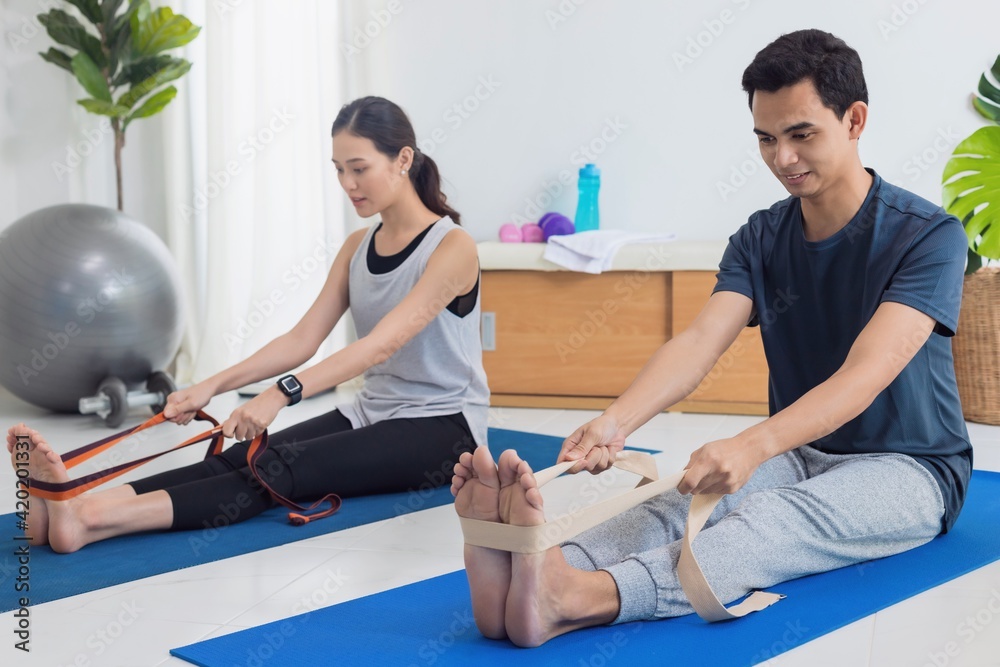 Obraz premium Asian young couple exercise together at home background.Concept of Exercise during the quarantine at home for preventing coronavirus and covid-19 infection.