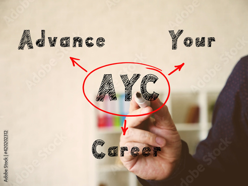 Conceptual photo about AYC Advance Your Career . Hand holding a marker pen to write on officce background. photo