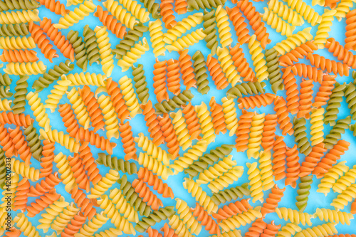 Creative food background with colorful fusilli on blue background