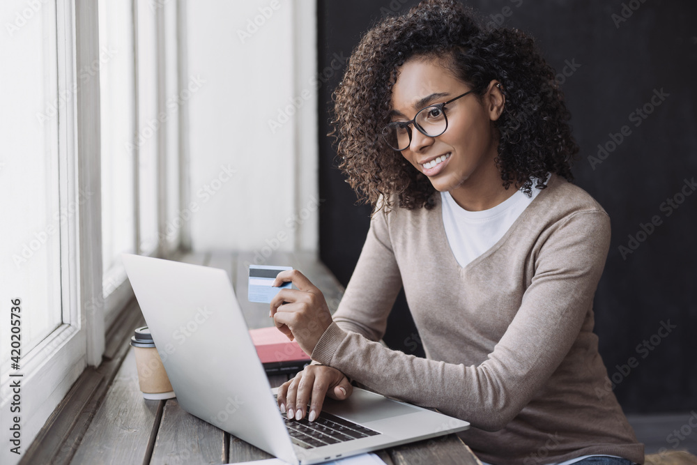 Young woman holding credit card and using laptop making payment online. Businesswoman or entrepreneur working at home. Online shopping, e-commerce, banking, internet store, spending money concept Young woman holding credit card and using laptop making payment online. Businesswoman or entrepreneur working at home. Online shopping, e-commerce, banking, internet store, spending money concept