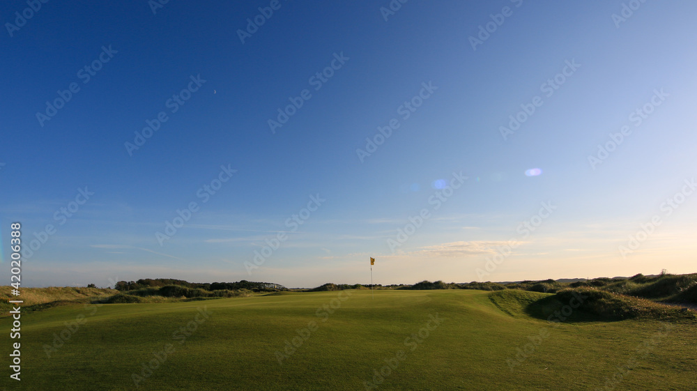 Golfcourse with clouds and sunrise with beautiful green grass and sky