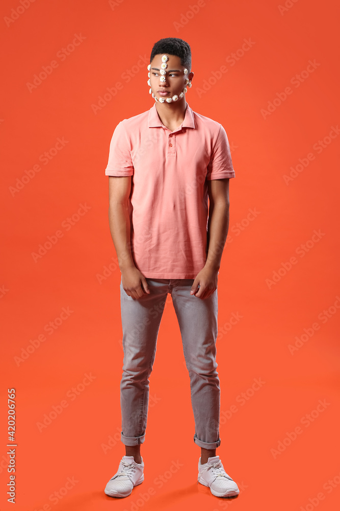 Portrait of handsome young man with flowers on face against color background Portrait of handsome young man with flowers on face against color background