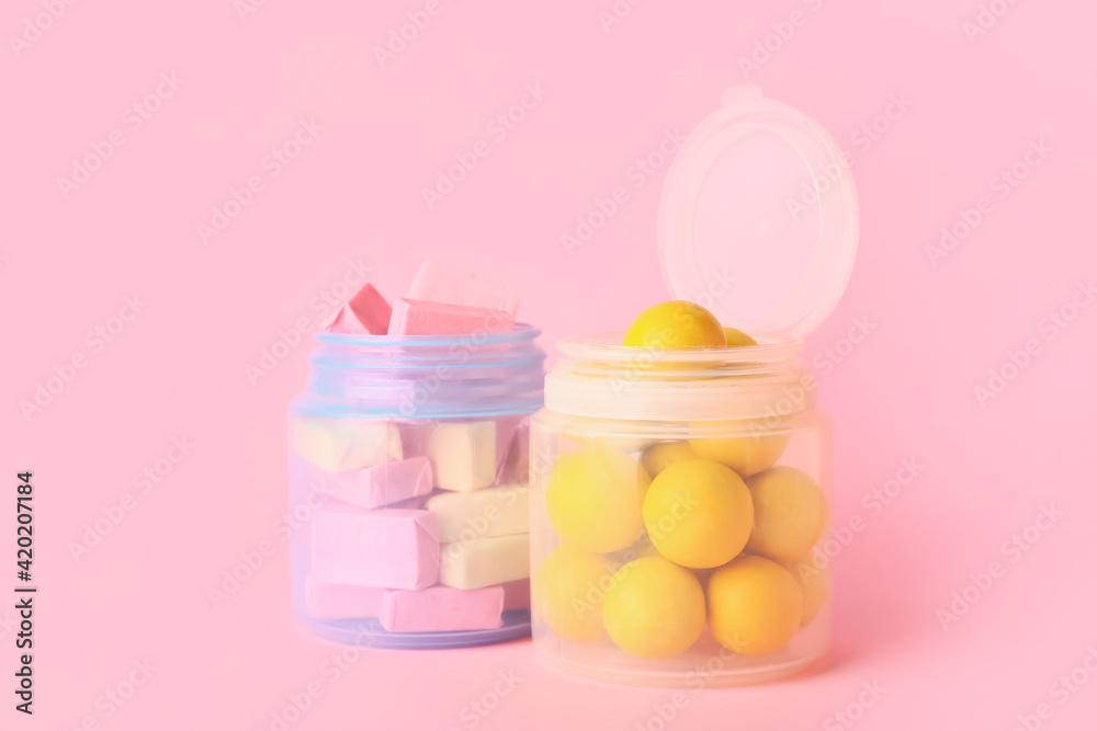 Jars with tasty chewing gums on color background