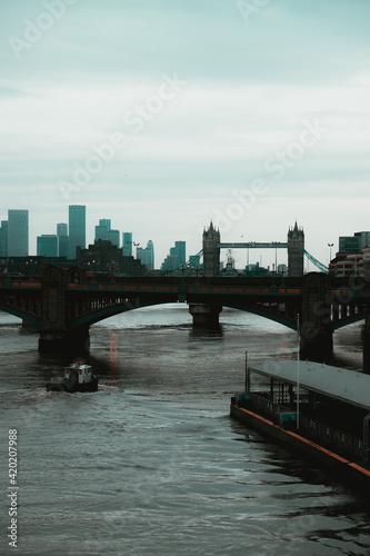 London UK February 2021 Vertical shot of the river thames on a cold winter day. Boats passing underneath the bridges, famous Tower Bridge in the distance