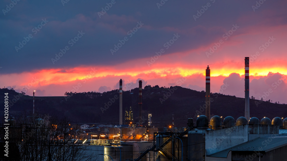 sunset with cloudy sky over industrial landscape with chimneys.