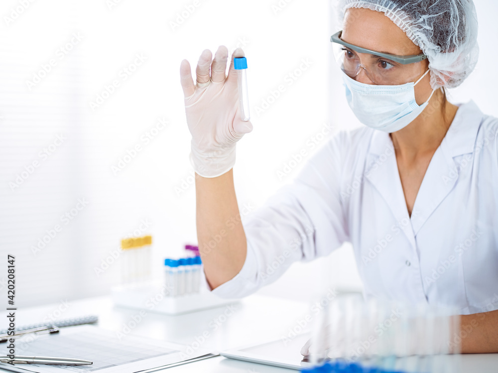 Professional female scientist in protective eyeglasses researching tube with reagents in laboratory. Concepts of medicine and science researching Professional female scientist in protective eyeglasses researching tube with reagents in laboratory. Concepts of medicine and science researching