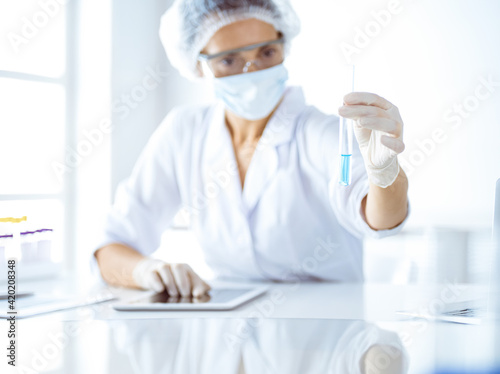 Professional female scientist in protective eyeglasses researching tube with reagents in laboratory. Concepts of medicine and science researching © rogerphoto